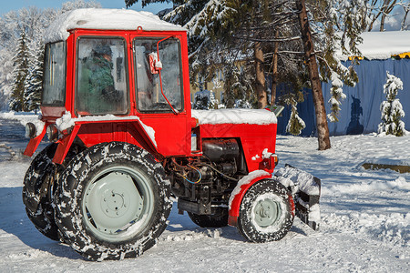 红拖拉机在下雪后从城市公园的徒步图片