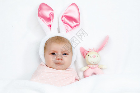 可爱的可爱新生女婴穿着复活节兔子服装和耳朵可爱的孩子在玩毛绒兔子玩图片