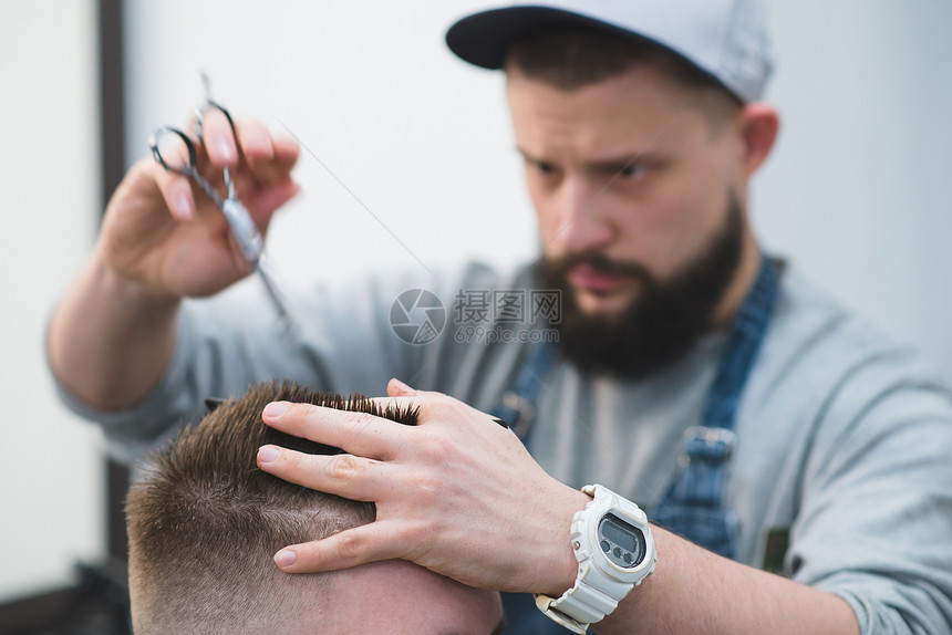 长胡子的理发师用剪刀和梳子剪头发图片