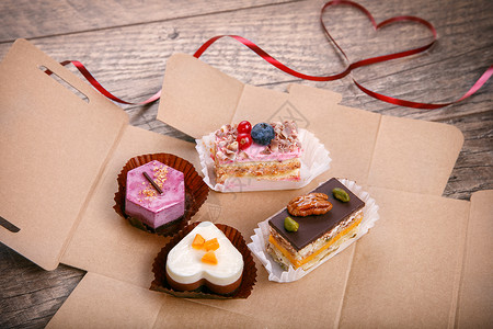 情人节的美味蛋糕红丝带在深色木桌上呈心形排列情人节背景图片