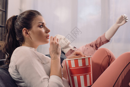 女人一边看电影边吃爆米花在家和马尼金一起看电影完美的图片