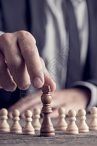 复古效果褪色和调的商人下棋移动黑色国王棋子的特写视图与白色棋子在图片