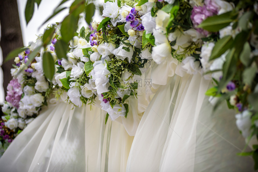 用鲜花白色椅子和鲜花束装饰的婚礼拱门图片