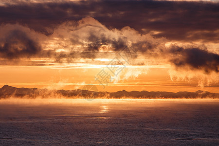 多云的日出在多山的海岸上面有云背景图片