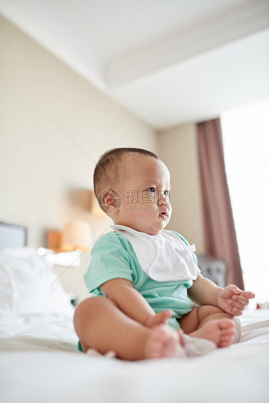 有打嗝布的沉思婴儿坐在床上图片