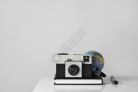 白色桌子上的旧胶片相机笔纸板笔和地球图片