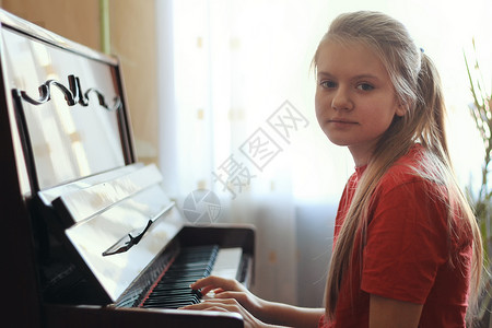 一个14岁的少女在家里弹钢琴的背景图片