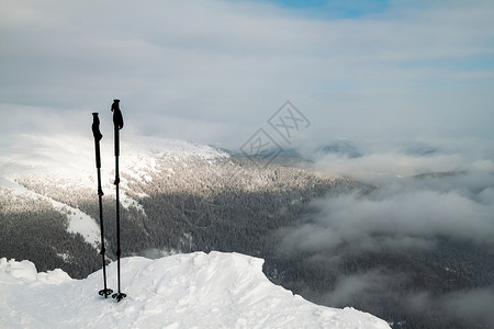 雪山顶上有两个滑雪杆背景是雪覆图片