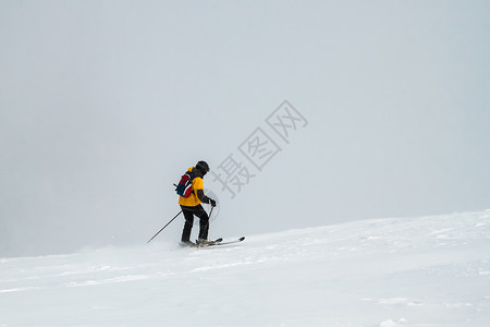 孤单滑雪者与滑雪杆一起在雪山上向前移图片