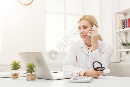 有吸引力的医生在办公室工作时与其中一位病人通过电话交谈图片