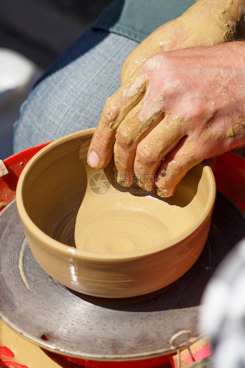 大师的手用陶器轮制造泥罐主的图片
