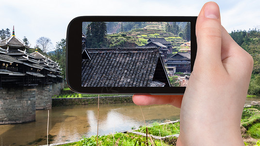 游客在春天用智能手机拍摄三江侗族自治县城阳风雨图片
