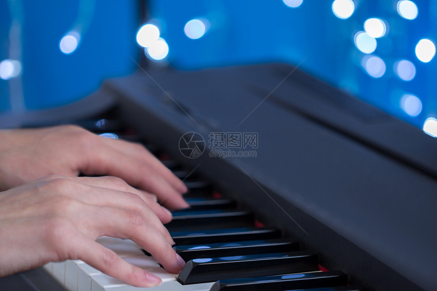 儿童双手在蓝布基背景浅深的田地上弹钢琴图片