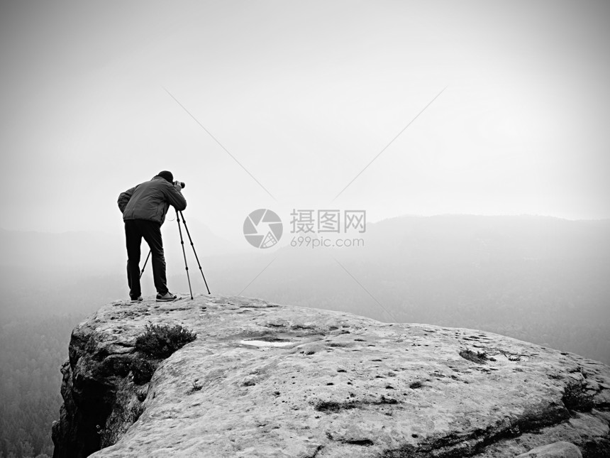 专业摄影师用镜像照相机和三脚架拍摄迷雾风景的照片图片