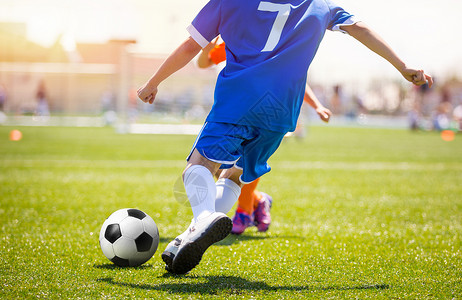 足球员跑球并踢向对手的球门背景是足球场夏日阳光明媚图片