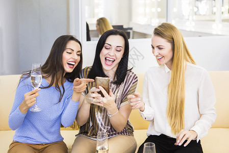 三个笑着的女朋友在喝香槟时从图片
