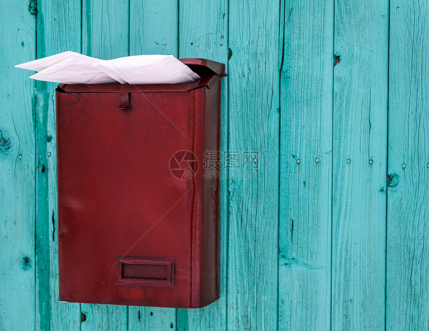 蓝色木墙上满是邮件的红色邮箱图片