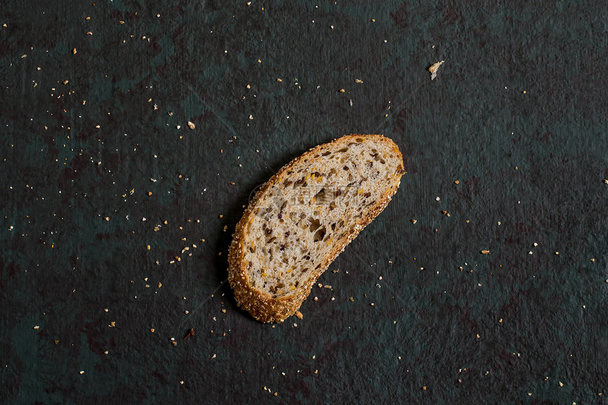 一片新鲜出炉的自制全麦面包和亚麻籽有用的不含酵母的膳食面包带切片和面包屑的绿图片