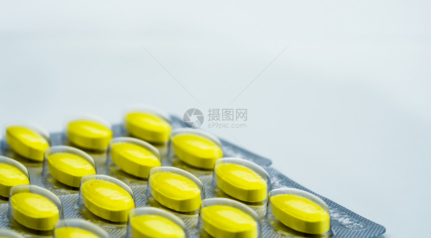 黄色椭圆形片剂药丸在白色背景上的泡罩包装中的宏观拍摄细节图片