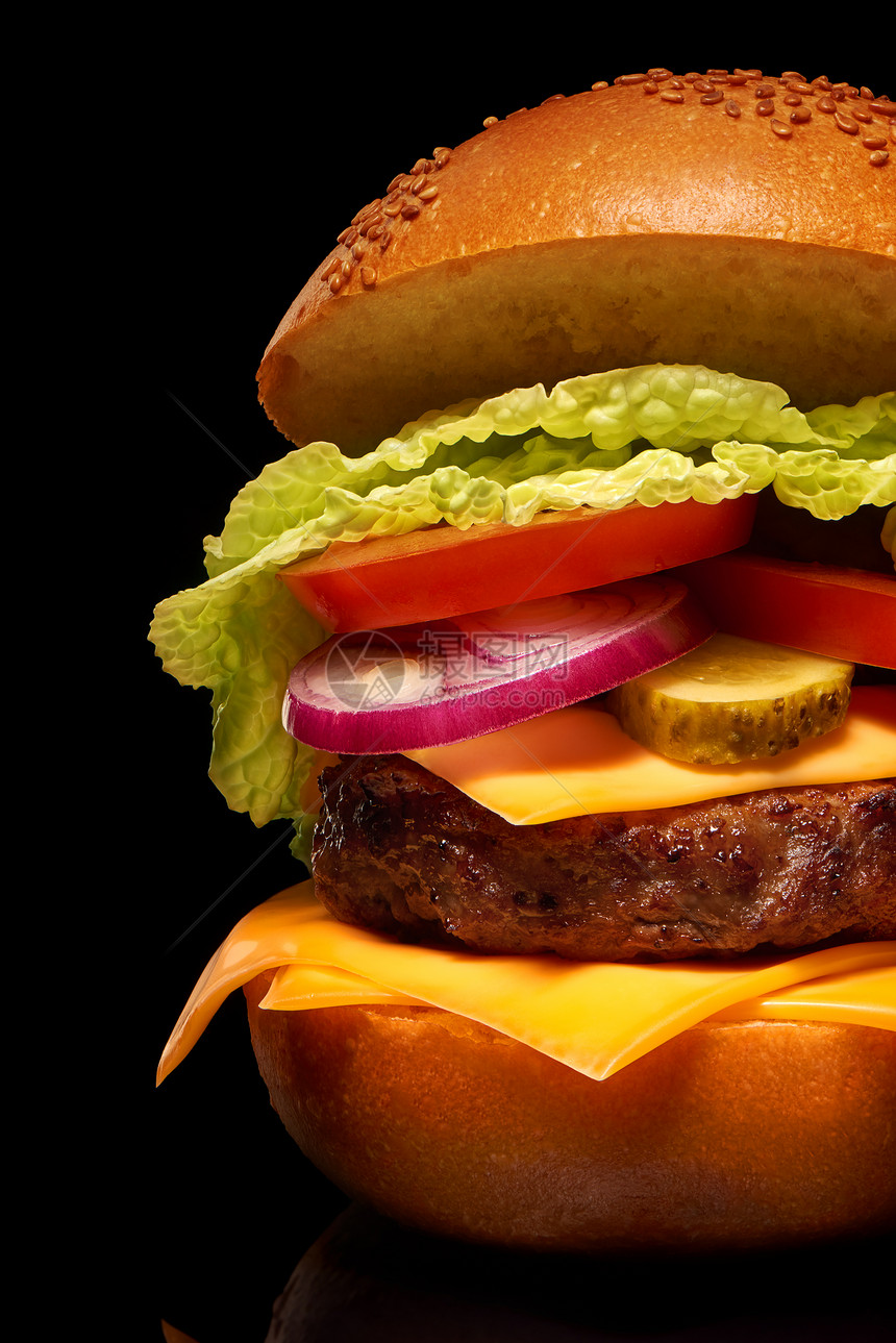 黑色背景中带奶酪泡菜番茄洋葱和生菜的美味汉堡包的图片