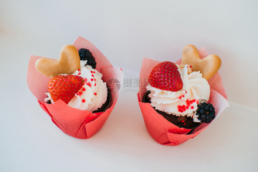 加奶油和新鲜草莓的纸杯蛋糕黑莓浆果和心形饼干图片