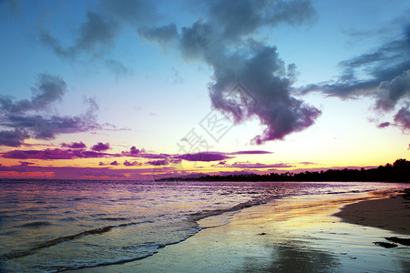 日出时的热带海滩背景与五颜六色的云彩在热带海滩上的五颜六色的图片