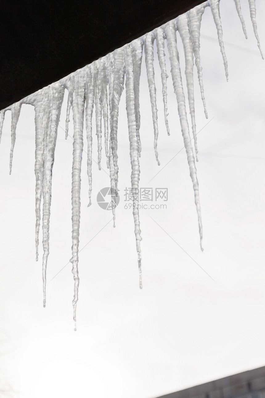 房子的雪顶上挂着危险的冰柱图片