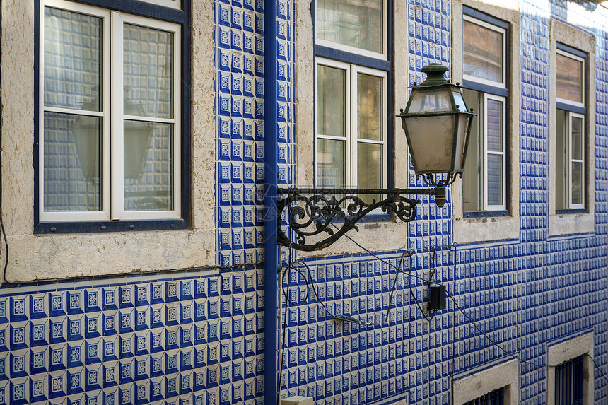 葡萄牙里斯本Alfama邻里区一栋有葡萄牙提莱斯Azulejo的旧楼和一座灯图片