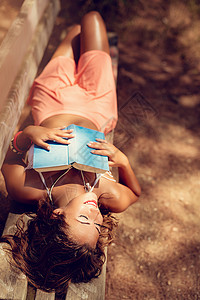 年轻女子在森林里轻松地阅读一本书图片