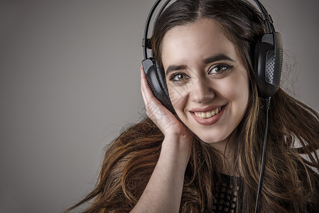 年轻女人拿着耳机听着她最喜欢的音乐和笑图片