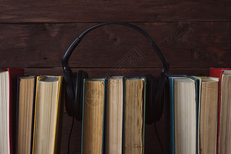 耳机放在深色木背景上的折叠书上图片