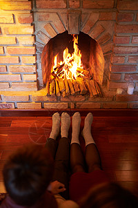 一对穿着袜子在客厅壁炉旁暖脚的情侣图片