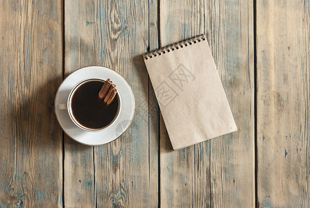 木桌背景的空白笔记本和咖啡杯带有设计复制空图片