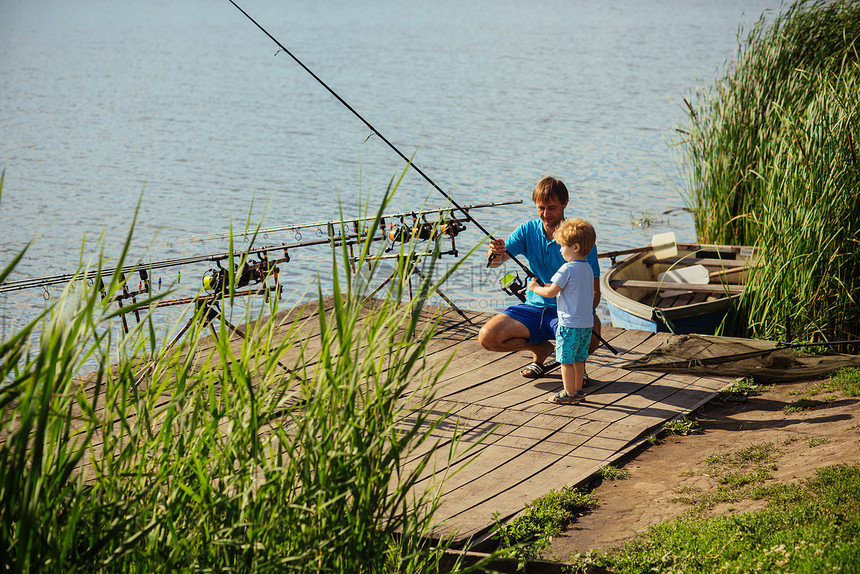 父亲教小儿子在淡水中钓鱼男人和孩子男孩在木码头上用钓竿鱼钓鱼垂钓活动冒险假期爱好生活方式家庭图片