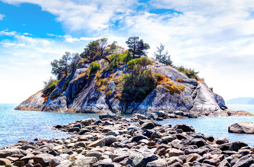 退潮时裸露的岩石通向位于加拿大不列颠哥伦比亚省西温哥华的怀特克里夫公园海滩的怀特克里夫岛上受欢迎的怀特岛公园图片
