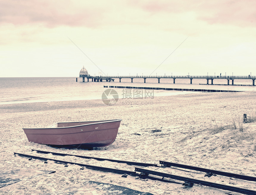 在沙滩上弃置的红桨船图片