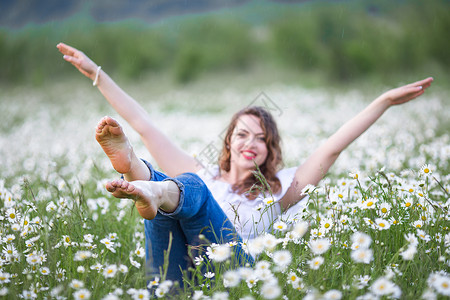 美丽的女人正在田野上放松用甘菊花图片