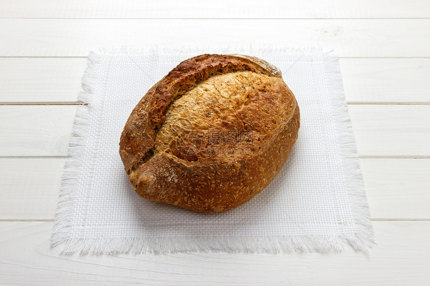 新鲜的自制全麦面包,餐巾上含麻籽图片