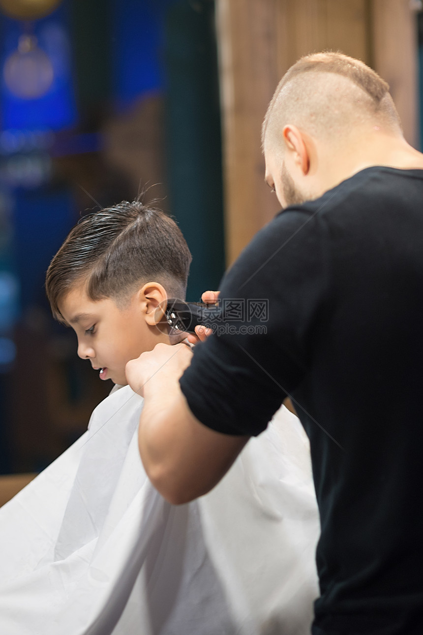 理发师给小学生做头发的年轻人图片