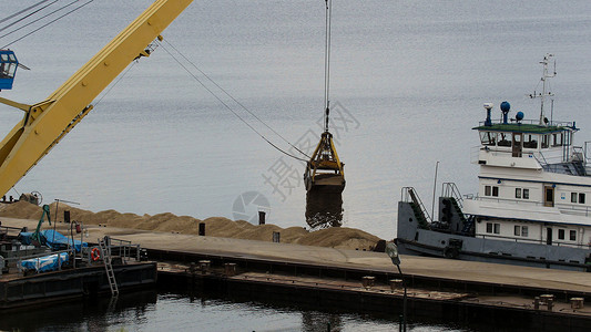 江河货运起重机从驳船向舶装载沙子的过图片