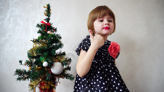 年轻漂亮的女孩在装饰着花环和球的圣诞树附近跳舞图片