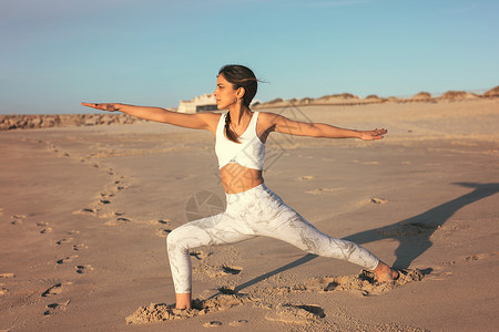 在海滩做瑜伽练习的型年轻女健康生活理念与身心发图片