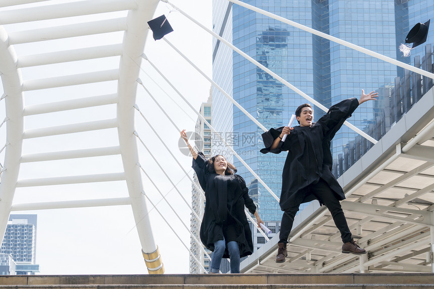 快乐的毕业生青少年在祝贺仪式上跳跃着毕业礼服图片