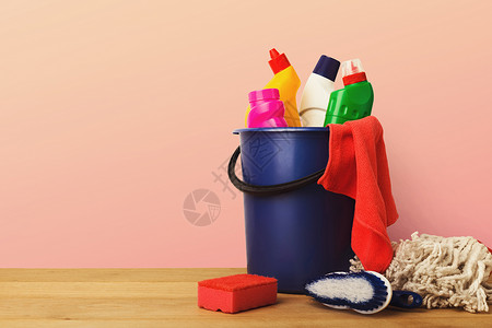 粉红色背景的木桌上的各种房屋清洁产品图片