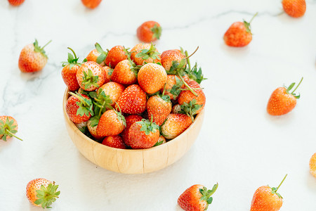 白石背景木碗中的草莓果图片