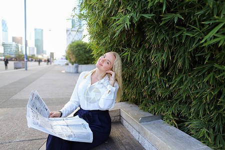 大众传媒和商业服装概念美丽的金发女子在绿色植物附近休息背景图片