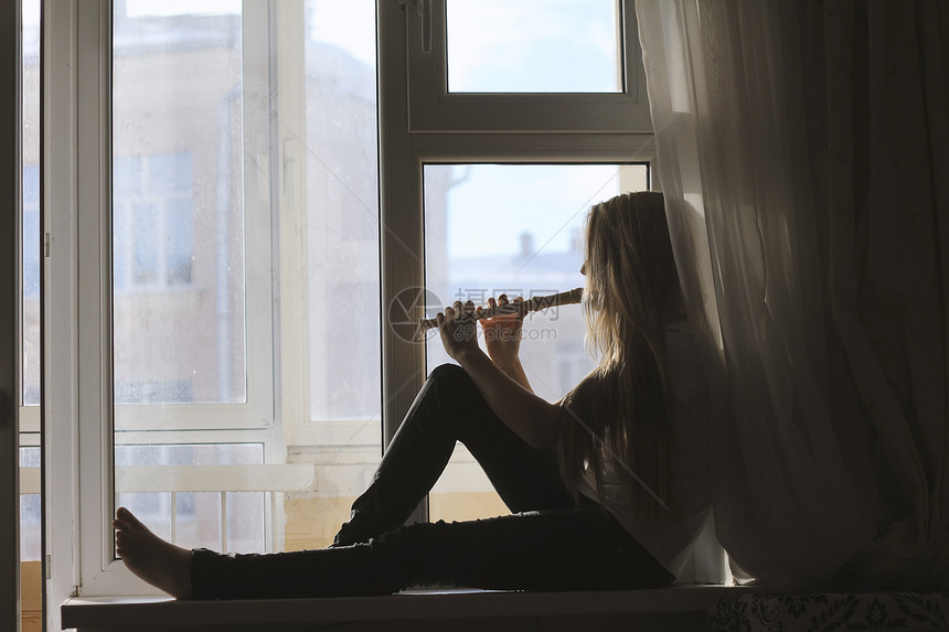 在家窗台上吹长笛的年轻可爱少女剪影青年爱图片