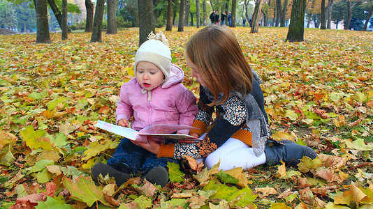 小女孩姐妹在秋天公园看书在大自然中休息秋天放松秋天公图片