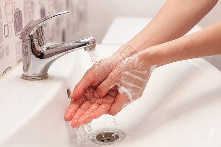 一名妇女正在自来水下洗手肥皂泡沫卫生洗手图片