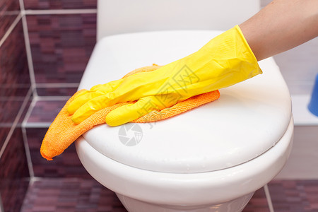 穿黄色橡胶手套的妇女用橙色衣服清洗马桶安全衣图片